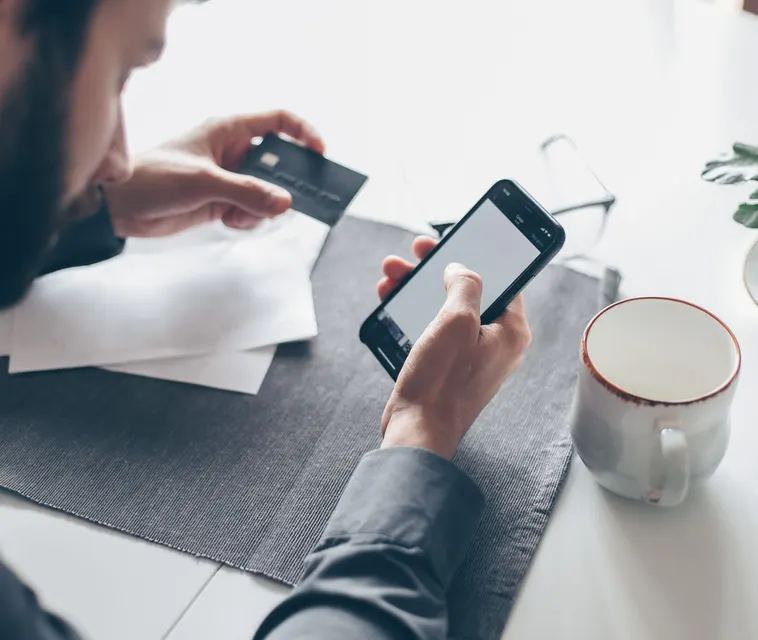 A man holding a bank card while setting up an account on his phone